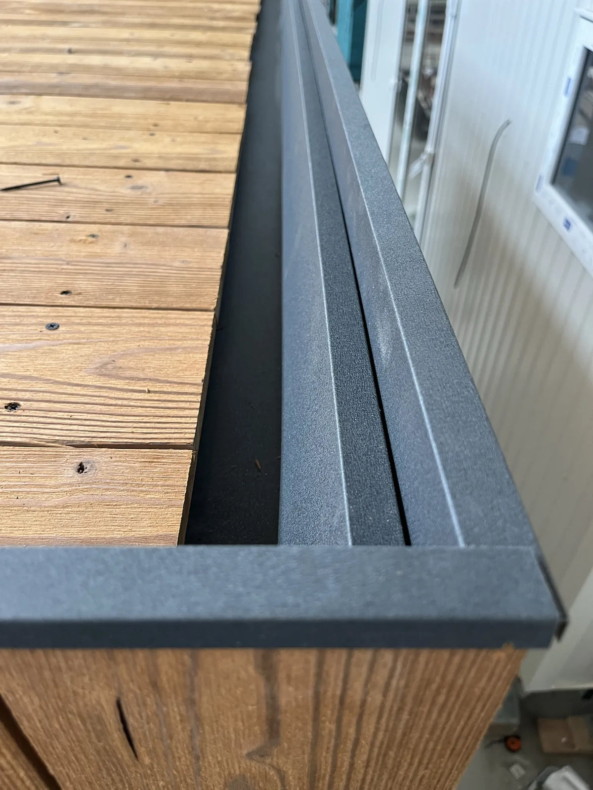Borde de la cubierta de un NOOK 10 en fábrica: tablas de madera, canalón y remate negro